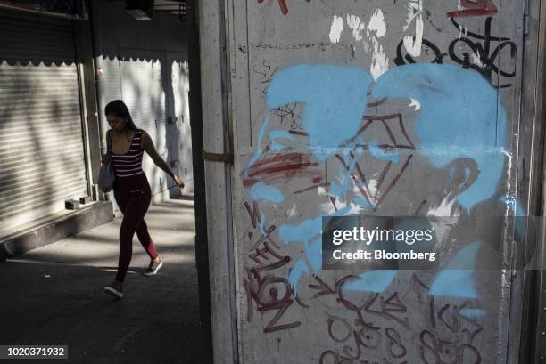 Woman walks past graffiti depicting an image of Venezuelan President Nicolas Maduro and late Venezuelan President Hugo Chavez in Caracas, Venezuela,...