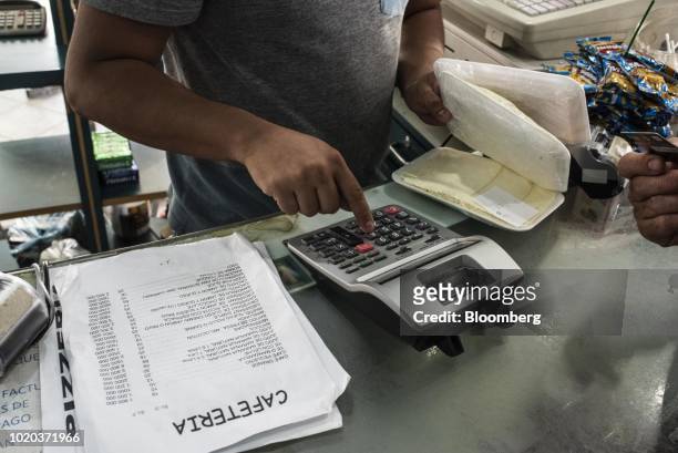 Vendor calculates food prices at a bakery in Caracas, Venezuela, on Monday, Aug. 20, 2018. The Venezuelan government is re-denominating the bolivar...