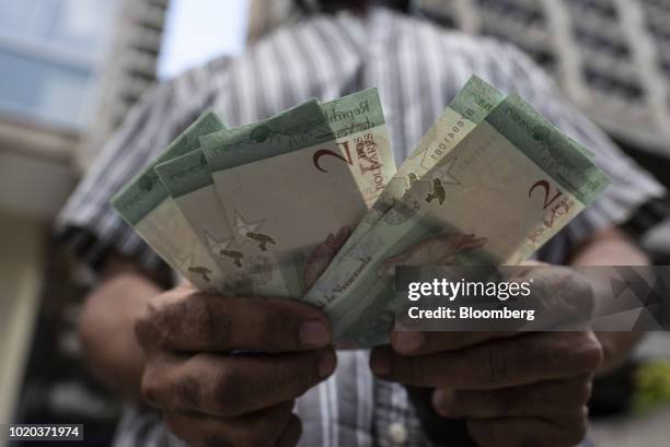 Man displays new 2 sovereign bolivar banknotes for a photograph after withdrawing them from an automated teller machine in Caracas, Venezuela, on...