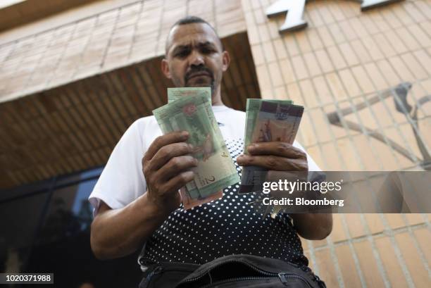 Man counts new 5 and 2 sovereign bolivar banknotes after withdrawing them from an automated teller machine in Caracas, Venezuela, on Monday, Aug. 20,...