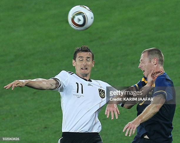 Germany's striker Miroslav Klose heads the ball next to Australia's defender Craig Moore during the Group D first round 2010 World Cup football match...