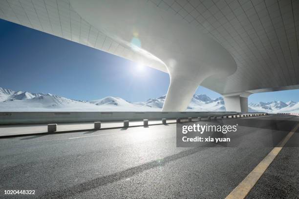 empty road with snow mountains - development summit stock pictures, royalty-free photos & images