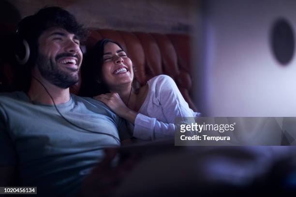 young couple watching a movie on a laptop. - cool couple in apartment stock pictures, royalty-free photos & images