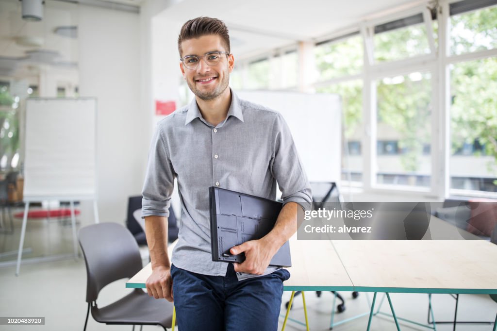Confident businessman standing by conference table