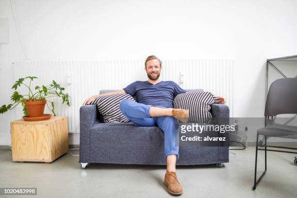 mitte adult geschäftsmann entspannend auf sofa - sitzen stock-fotos und bilder