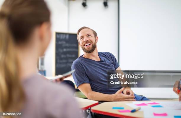 lachende zakenman te praten met collega's op kantoor - cool office stockfoto's en -beelden