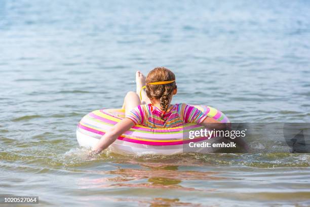 vista posterior de la muchacha flotando en el interior del tubo en agua - tube girl fotografías e imágenes de stock