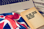 A computer, flag of Great Britain and book titled Speak English