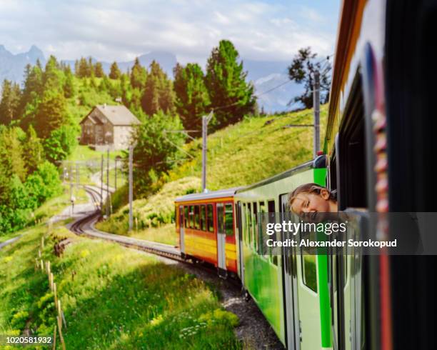 little girl looking through the window of alpine train - bambino treno foto e immagini stock