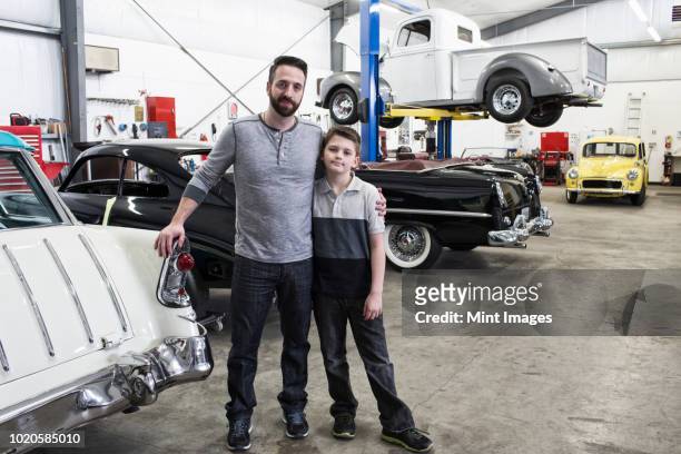 a portrait of a caucasian male and his young son in their classic car repair shop. - classic day 2 stockfoto's en -beelden