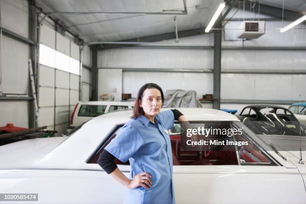 a portrait of a caucasian female mechanic in a car repair shop. - old car garage stock pictures, royalty-free photos & images