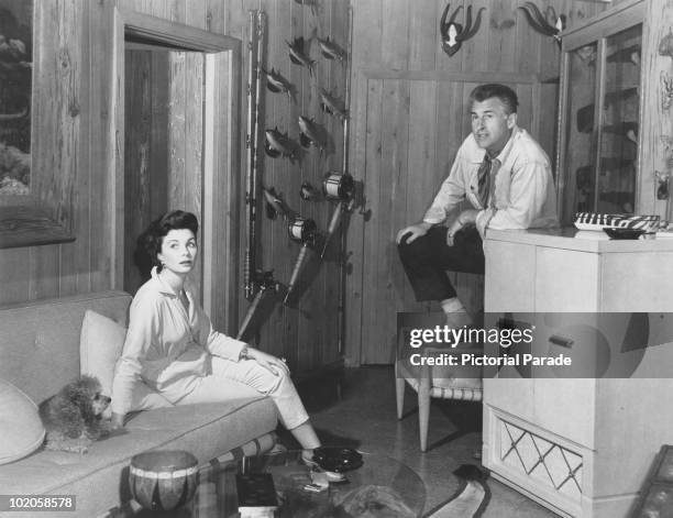 Married English actors Stewart Granger and Jean Simmons at home with their pet poodle, circa 1955. On the wall are some of Granger's hunting and...