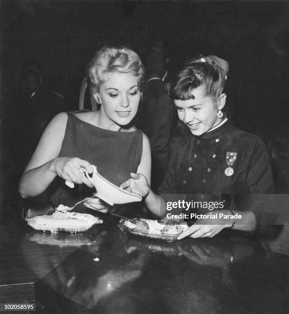 American actresses Kim Novak and Debbie Reynolds enjoying ice cream sundaes at a Hollywood party, circa 1955.