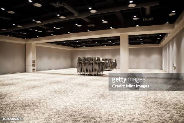 stacked chairs in an empty convention centre meeting room. - empty conference centre stock pictures, royalty-free photos & images
