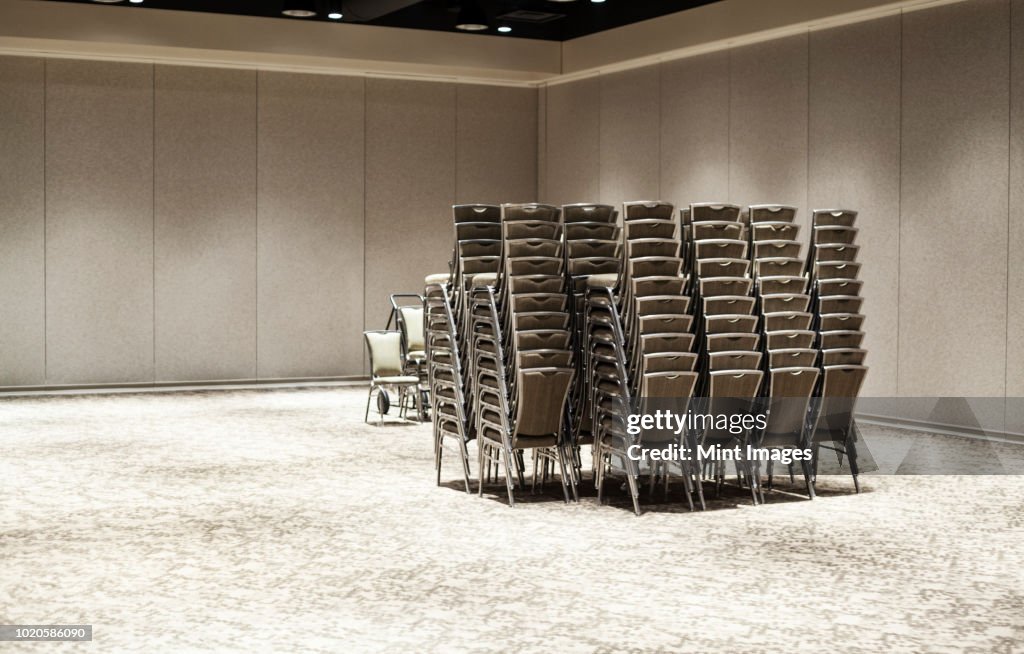 Stacked chairs in an empty convention centre meeting room.