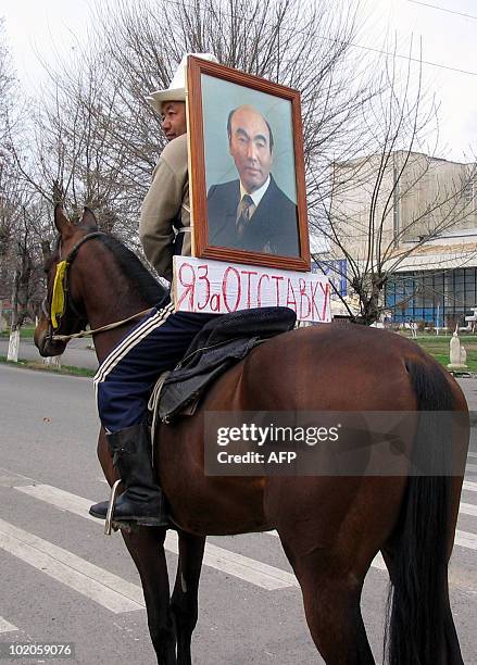 Supporter of the Kyrgyz opposition rides a horse with a portrait of President Askar Akayev attached On his back and a banner reading "I am for...