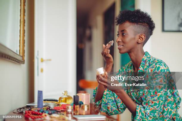young woman applying a moisturiser in the morning - woman backstage stock pictures, royalty-free photos & images