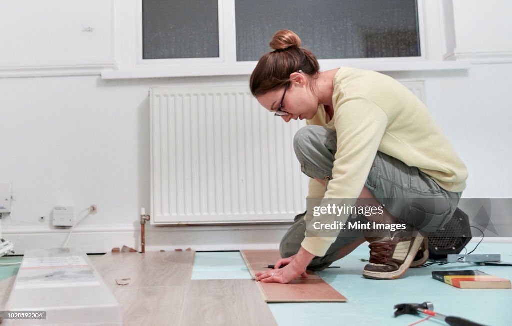 Woman fitting new floor boards, house renovation