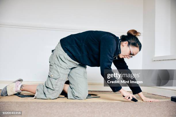 woman using knife to cut away a carpet on a room floor - tabla de piso fotografías e imágenes de stock