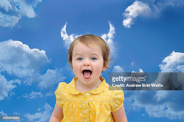baby girl in a yellow dress under cloud horns - devil stock-fotos und bilder