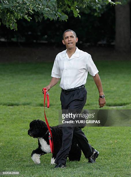 President Barack Obama walks the first family's dog as he arrives at the Congressional Picnic on the South Lawn of the White House in Washington, DC...