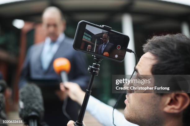 Journalist records video on a mobile phone as Sir Norman Bettison gives a statement after he was granted a stay of proceedings during a hearing at...