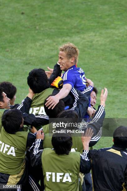 Keisuke Honda of Japan celebrates scoring the opening goal with his team mates during the 2010 FIFA World Cup South Africa Group E match between...