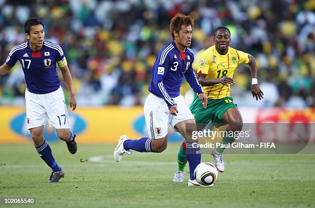 Yuichi Komano of Japan is chased by Eyong Enoh of Cameroon during the 2010 FIFA World Cup South Africa Group E match between Japan and Cameroon at...
