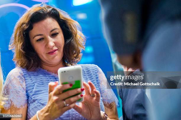 German State Minister for Digitization Dorothee Baer tries an app on a smartphone at 2018 Gamescom video games trade fair press day on August 21,...