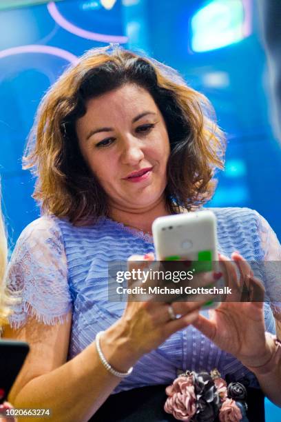 German State Minister for Digitization Dorothee Baer tries an app on a smartphone at 2018 Gamescom video games trade fair press day on August 21,...