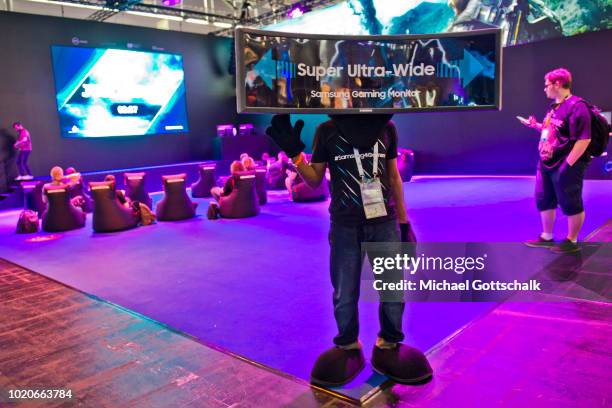 Steward wears a super ultra wide videoscreen on his head to guide visitors to Samsung booth at 2018 gamescom fair press day on August 21, 2018 in...