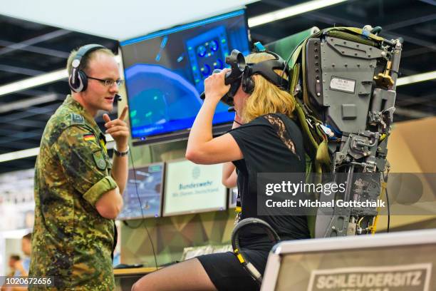 Visitors sits on a catapult seat at German Army Bundeswehr recruiting booth at 2018 gamescom fair press day on August 21, 2018 in Cologne, Germany....