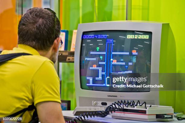 Visitors tries a retro video game at 2018 gamescom fair press day on August 21, 2018 in Cologne, Germany. Gamescom is Europe's biggest trade fair for...