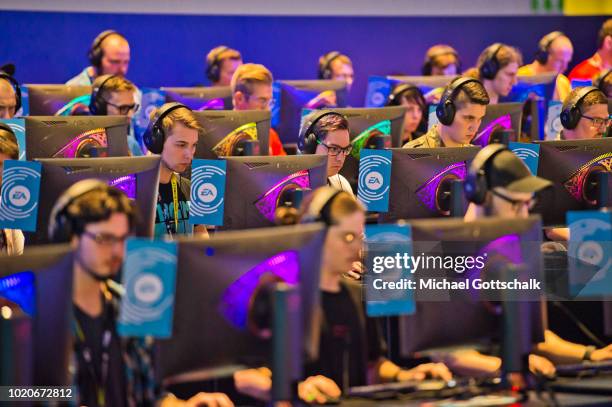 Visitors try video games at EA booth at 2018 gamescom fair press day on August 21, 2018 in Cologne, Germany. Gamescom is Europe's biggest trade fair...