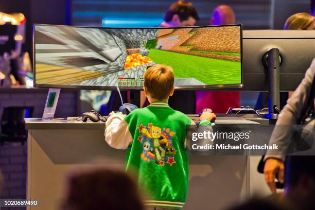 Young boy tries a video game on a super ultra wide videoscreen at 2018 gamescom fair press day on August 21, 2018 in Cologne, Germany. Gamescom is...