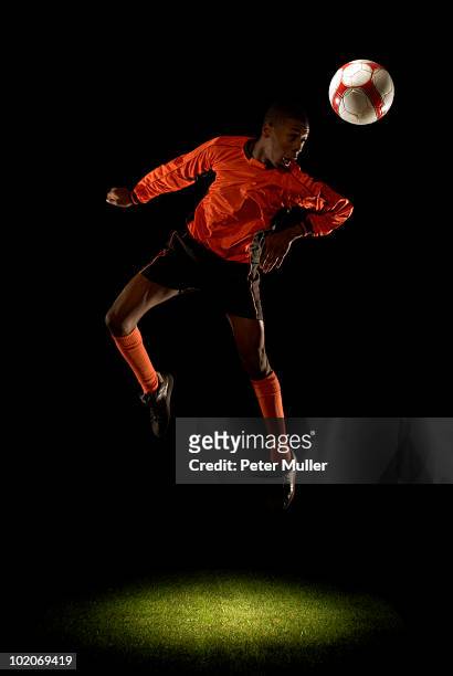 footballer heading ball - black football player stock pictures, royalty-free photos & images