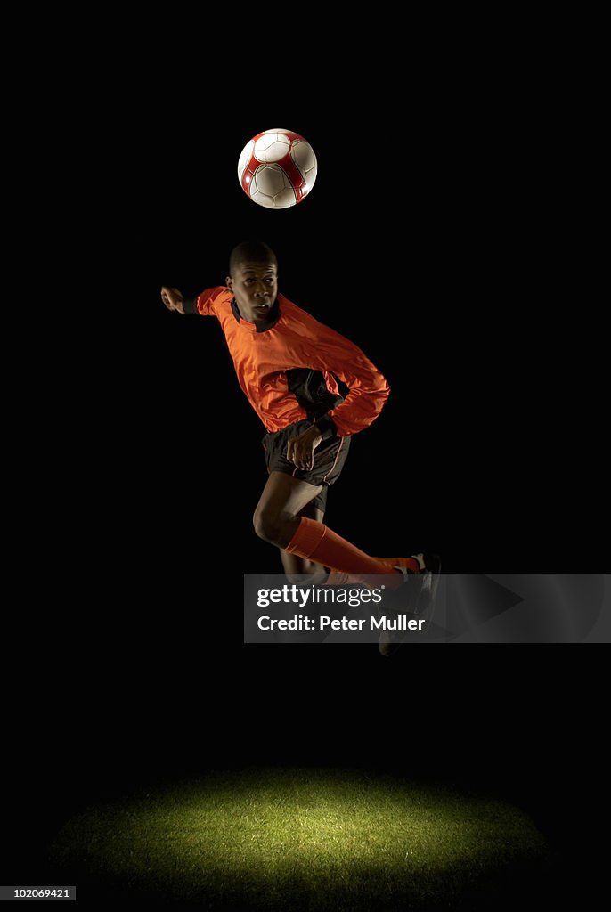 Footballer mid air heading ball