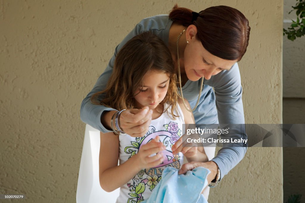 Mother helping daughter sew