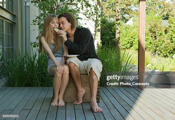 young man feeding young woman a sandwich - teen girl barefoot stock pictures, royalty-free photos & images