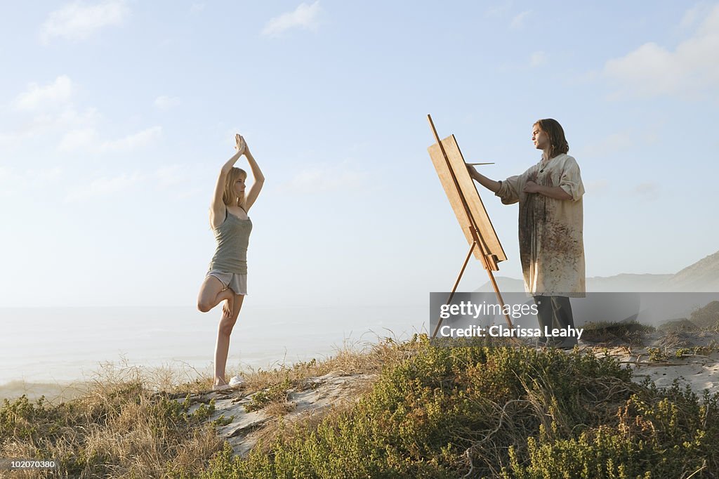 Young man painting girl in landscape