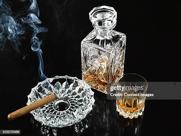 Cigar In Ashtray With Decanter And Tumbler Of Whiskey, Foto stock
