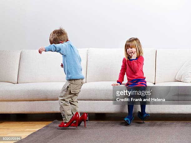 young boy and girl walking in high-heels - rolwisseling stockfoto's en -beelden