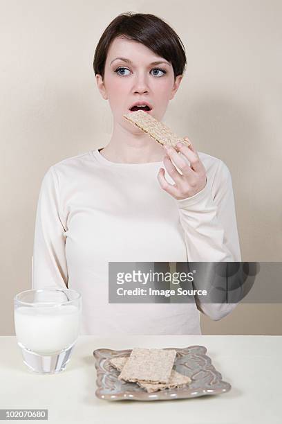 young woman eating savoury crackers - cracker snack 個照片及圖片檔