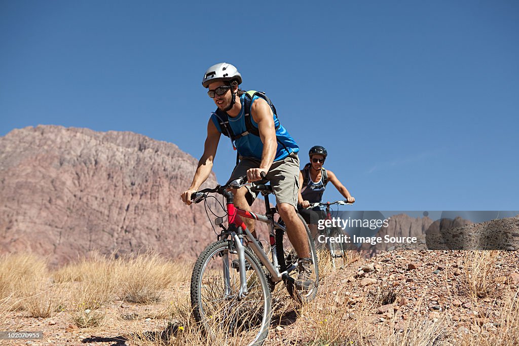 Hombre y mujer en bicicleta de montaña en terreno rocoso