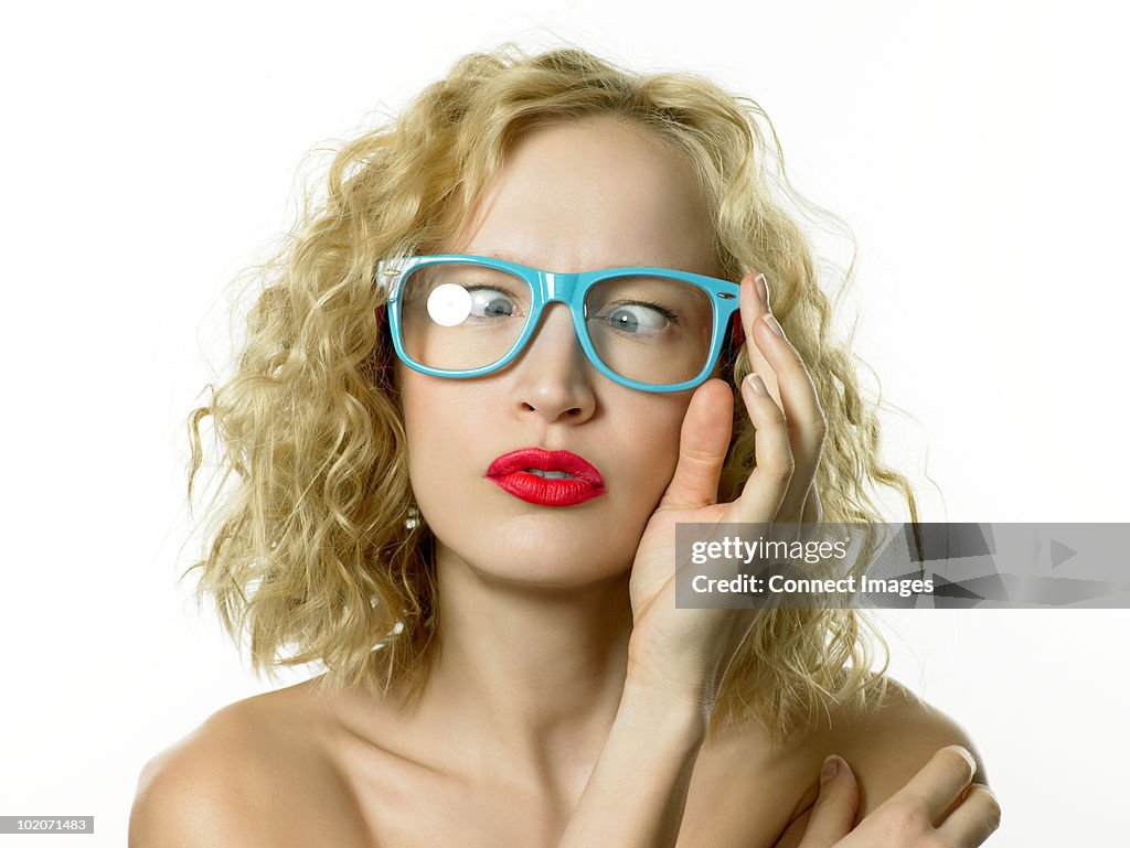 Young woman wearing blue glasses, cross eyed