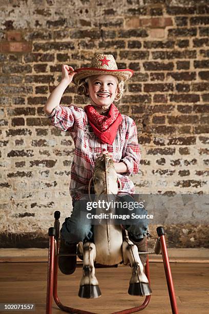 young girl dressed as cowgirl with rocking horse - girl and blond hair and cowboy hat stock pictures, royalty-free photos & images