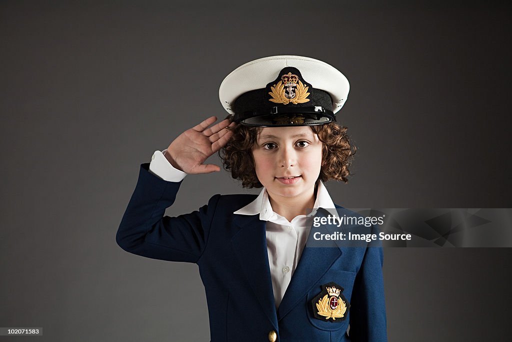 Young boy dressed up in sailor outfit, saluting
