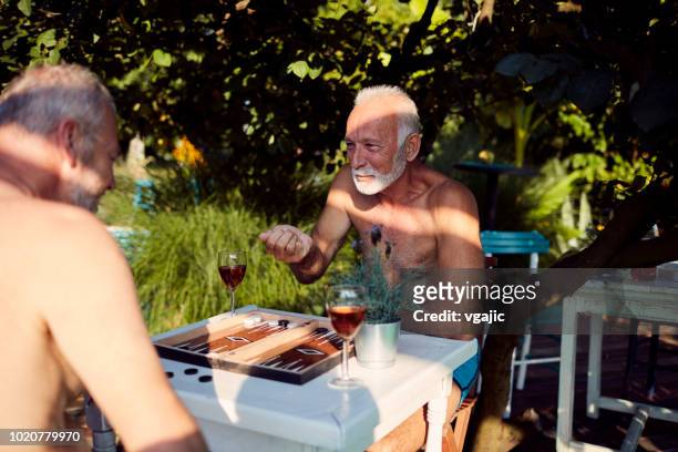 seniors men playing backgammon on summer vacation - backgammon stock pictures, royalty-free photos & images