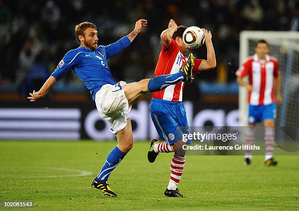 Daniele De Rossi of Italy kicks the ball while Jonathan Santana of Paraguay tries to block the ball during the 2010 FIFA World Cup South Africa Group...