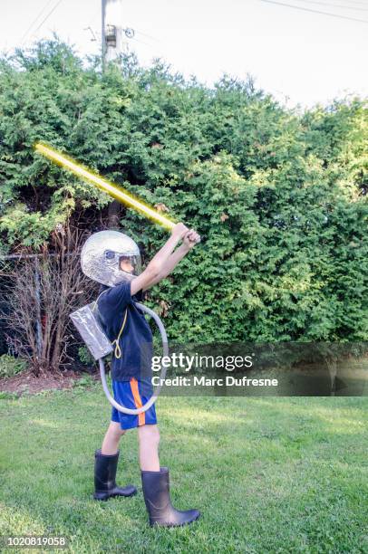 young boy dressed as an astronaut in the backyard during summer day - lightsaber stock pictures, royalty-free photos & images